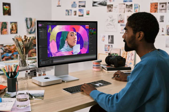 Ai đó đang sử dụng Mac Mini khi ngồi ở bàn làm việc.